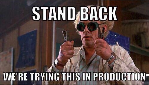 Doc Brown from Back to the Future in welding goggles, holding two cables, captioned "Stand back, we're trying this in production"